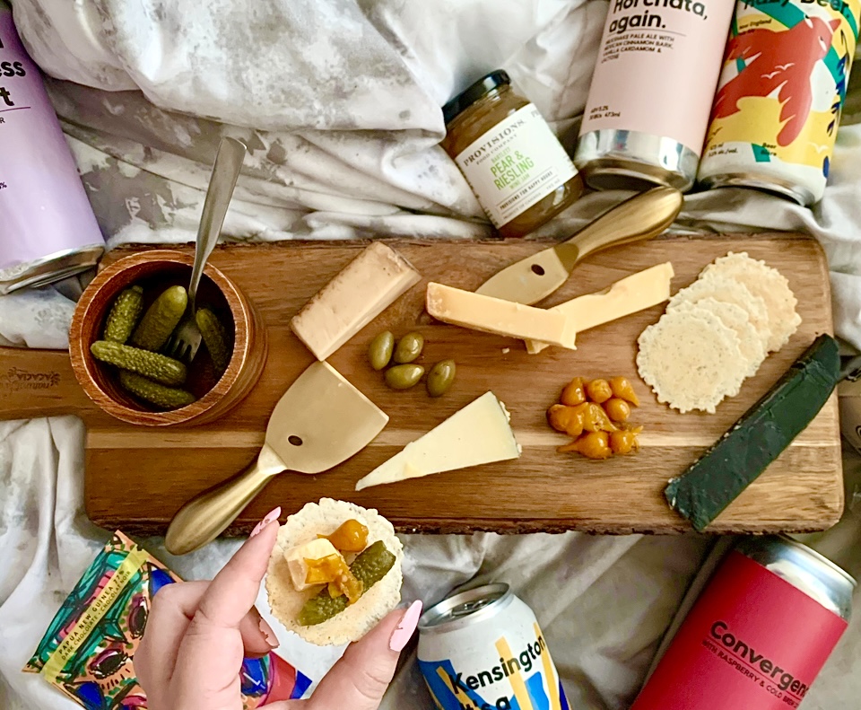 A hand holding a cracker with charcuterie